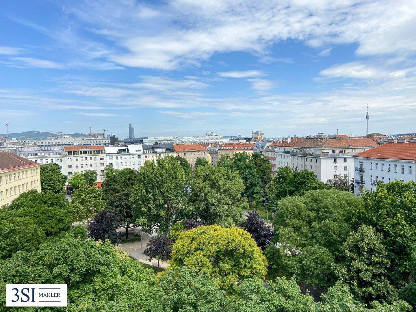 Weitläufiger Blick über die Stadt mit vielen grünen Baumkronen und urbaner Bebauung.