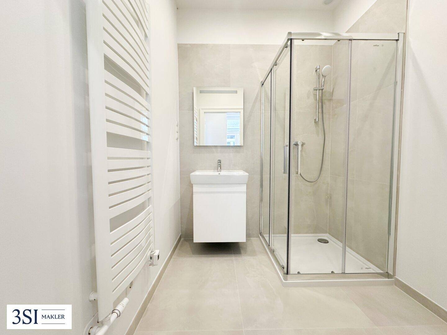 Modernes Badezimmer mit Duschkabine, Waschbecken und beheiztem Handtuchhalter.