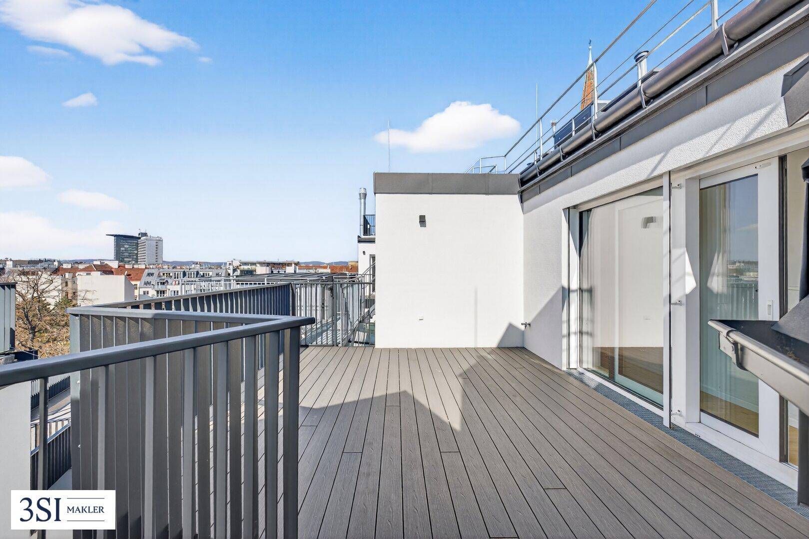 Geräumige Dachterrasse mit Holzboden und Blick auf die umliegenden Gebäude und den Himmel.