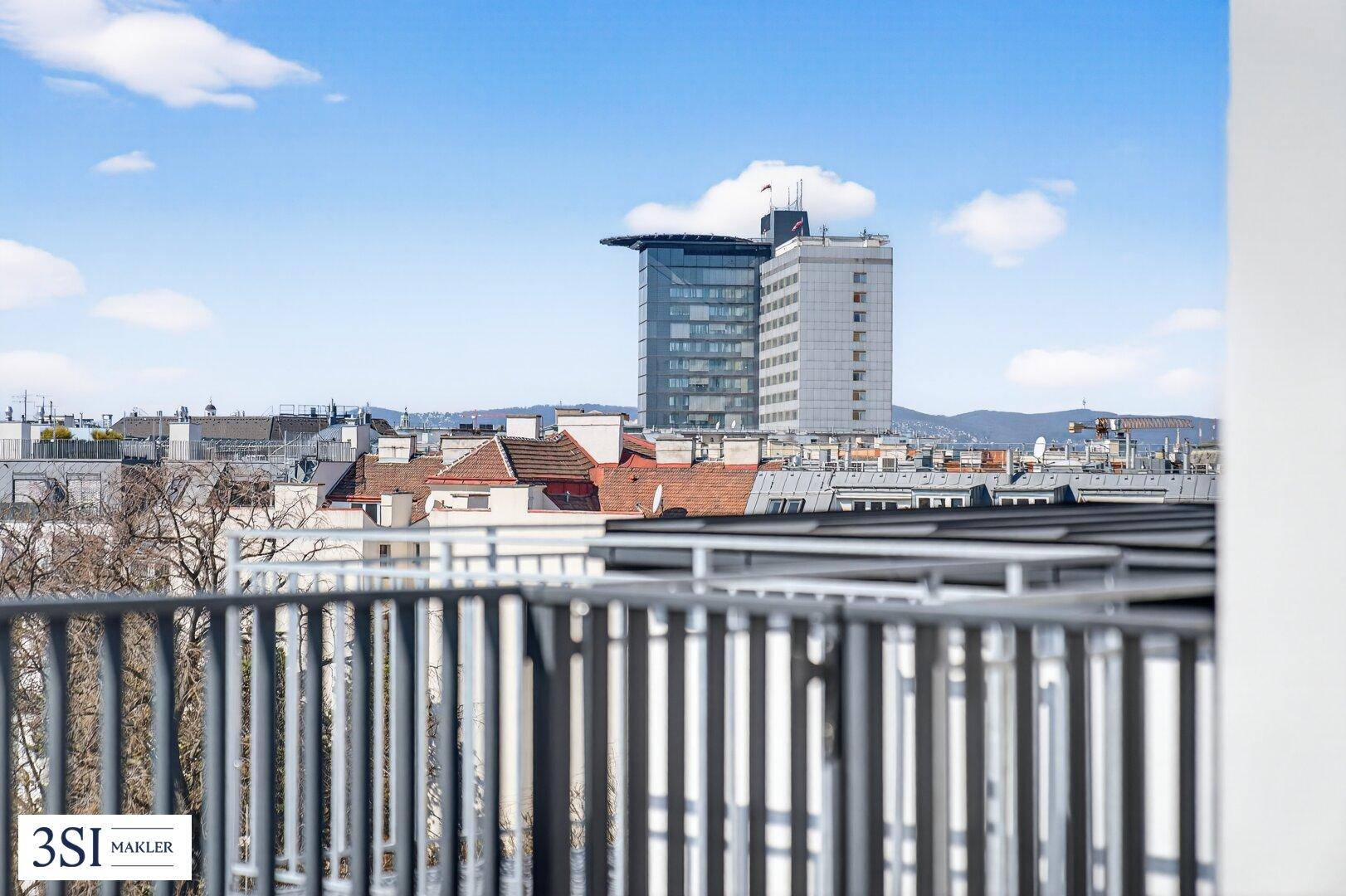 Weitläufiger Stadtblick von der Dachterrasse mit modernen Gebäuden und blauem Himmel im Hintergrund.