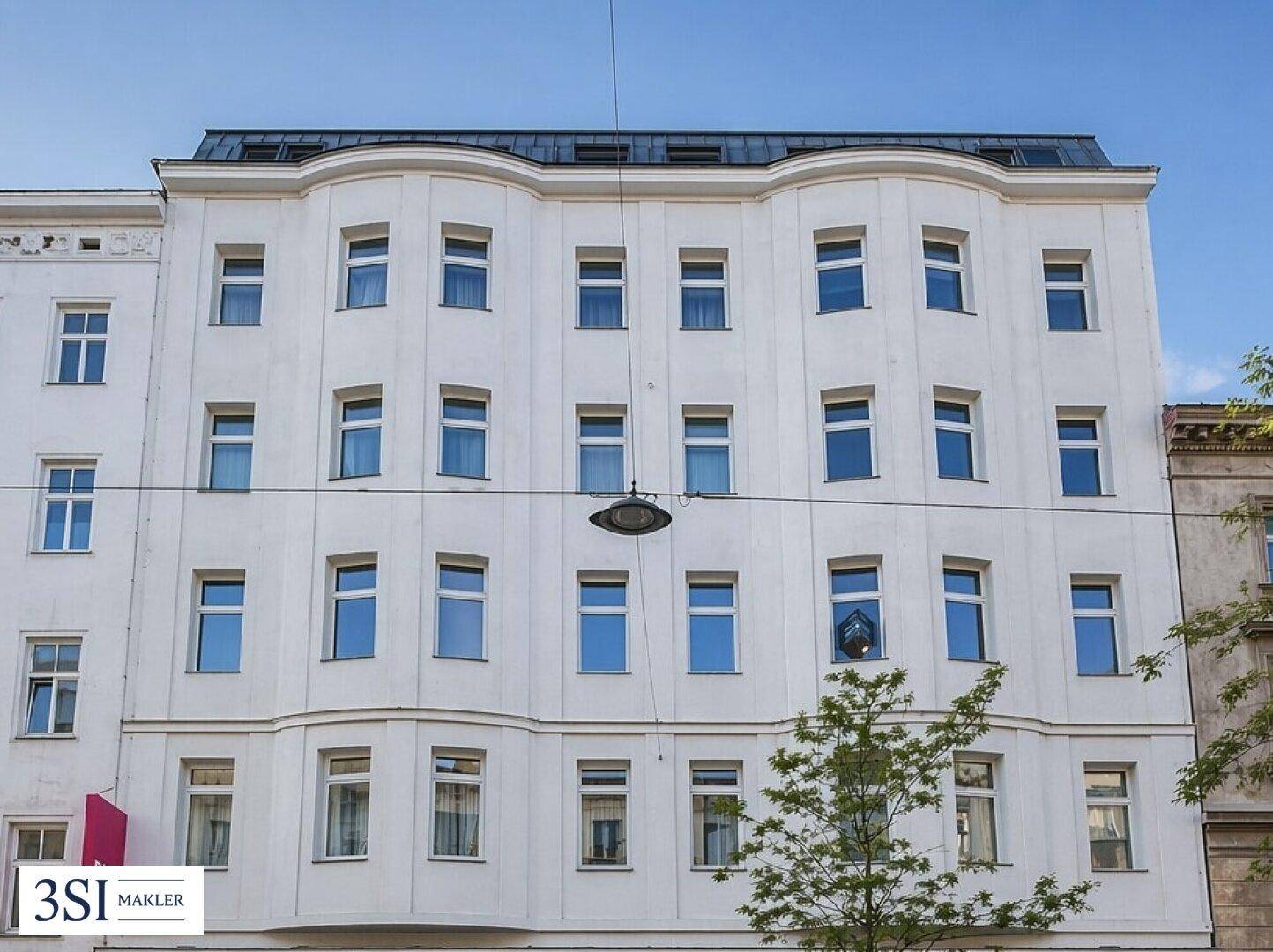 Klassische Altbaufassade mit vielen Fenstern und einem Mansarddach in der Stadt.