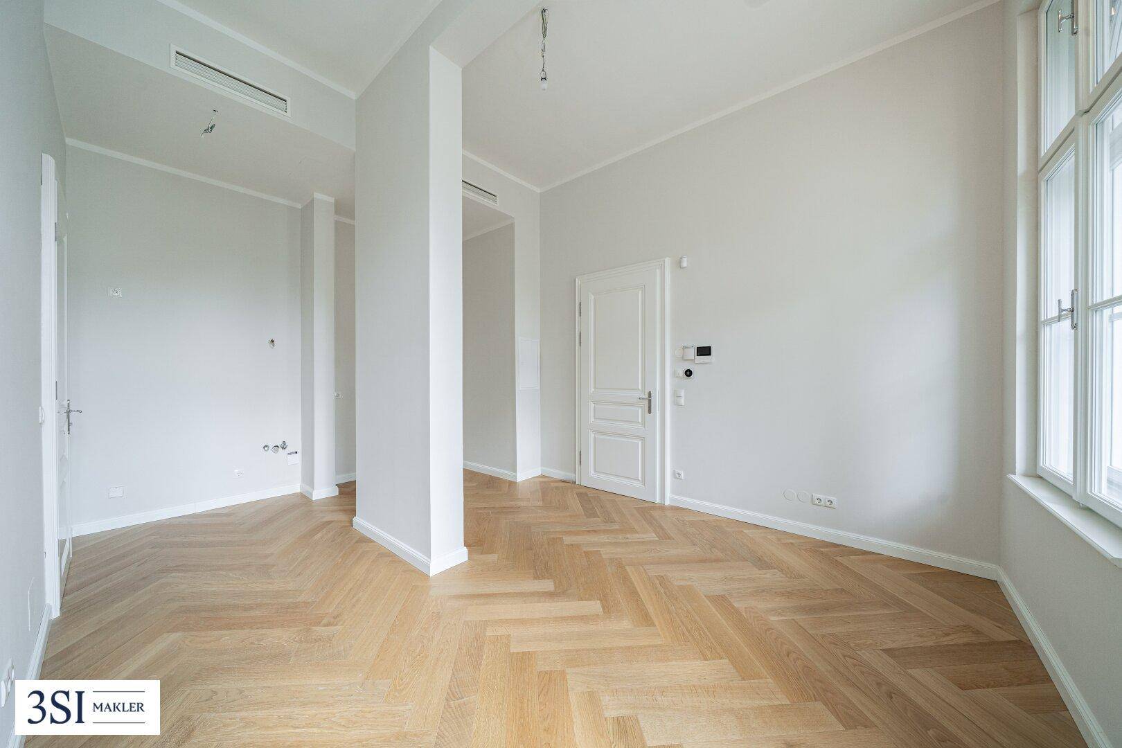 Geräumiger Raum mit Fischgrätparkett und schlichter Eleganz, ideal für vielfältige Nutzung.