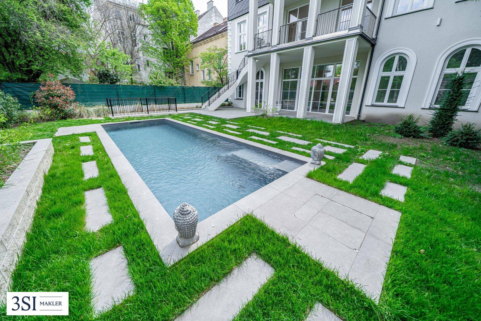 Moderner Gartenbereich mit rechteckigem Pool, gepflegtem Rasen und stilvollen Steinplattenwegen.