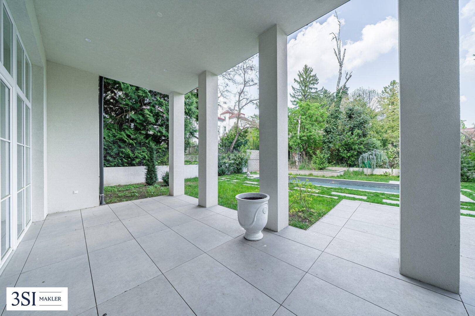 Überdachte Terrasse mit großen Säulen und Blick auf den grünen Gartenbereich.