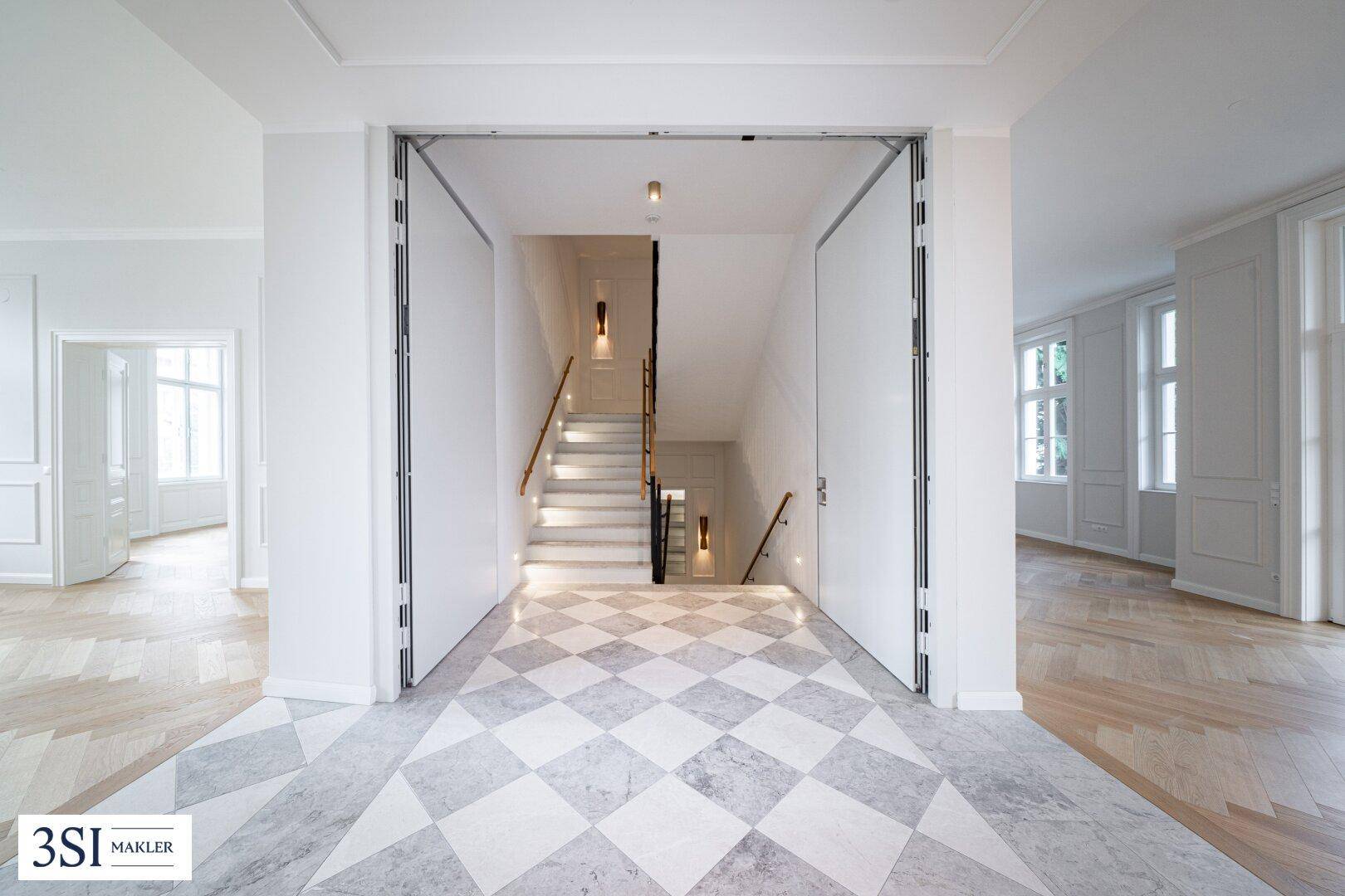 Geräumiger Flur mit Marmorboden, eleganter Treppe und hohen Decken.