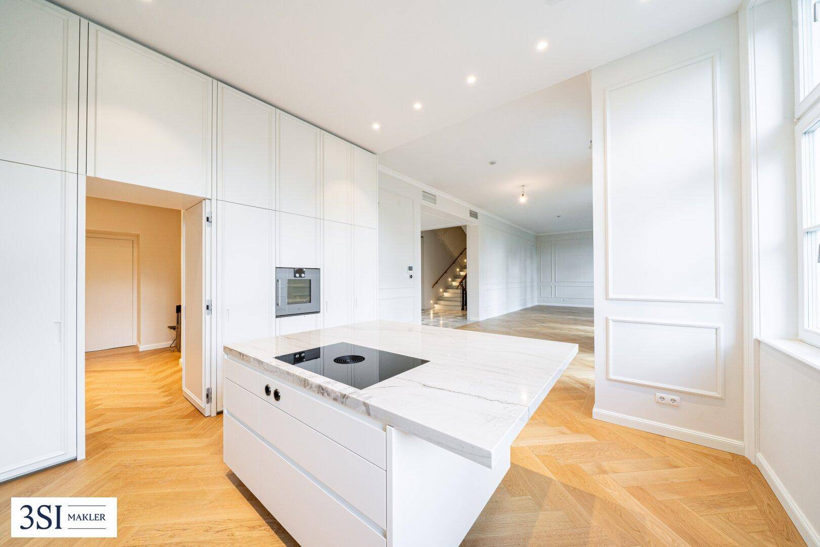Moderne, helle Küche mit Kochinsel, integrierten Geräten und Fischgrätparkettboden.