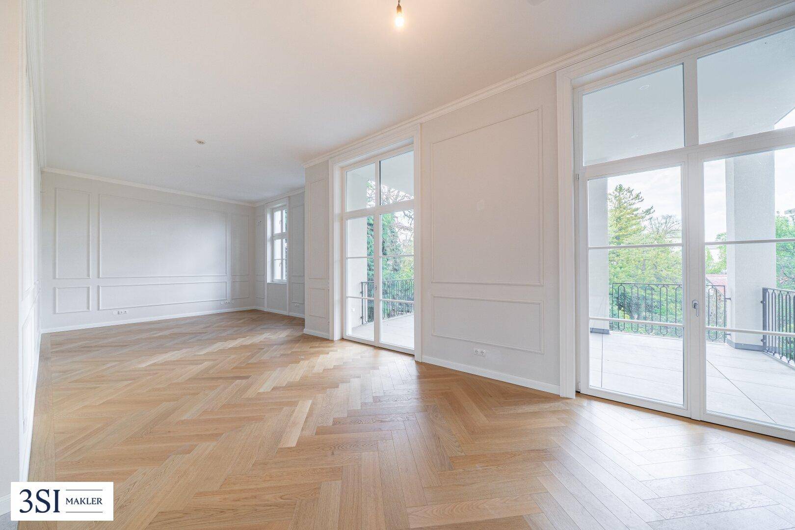 Großes Wohnzimmer mit Fischgrätparkett und direktem Zugang zu einem Balkon.