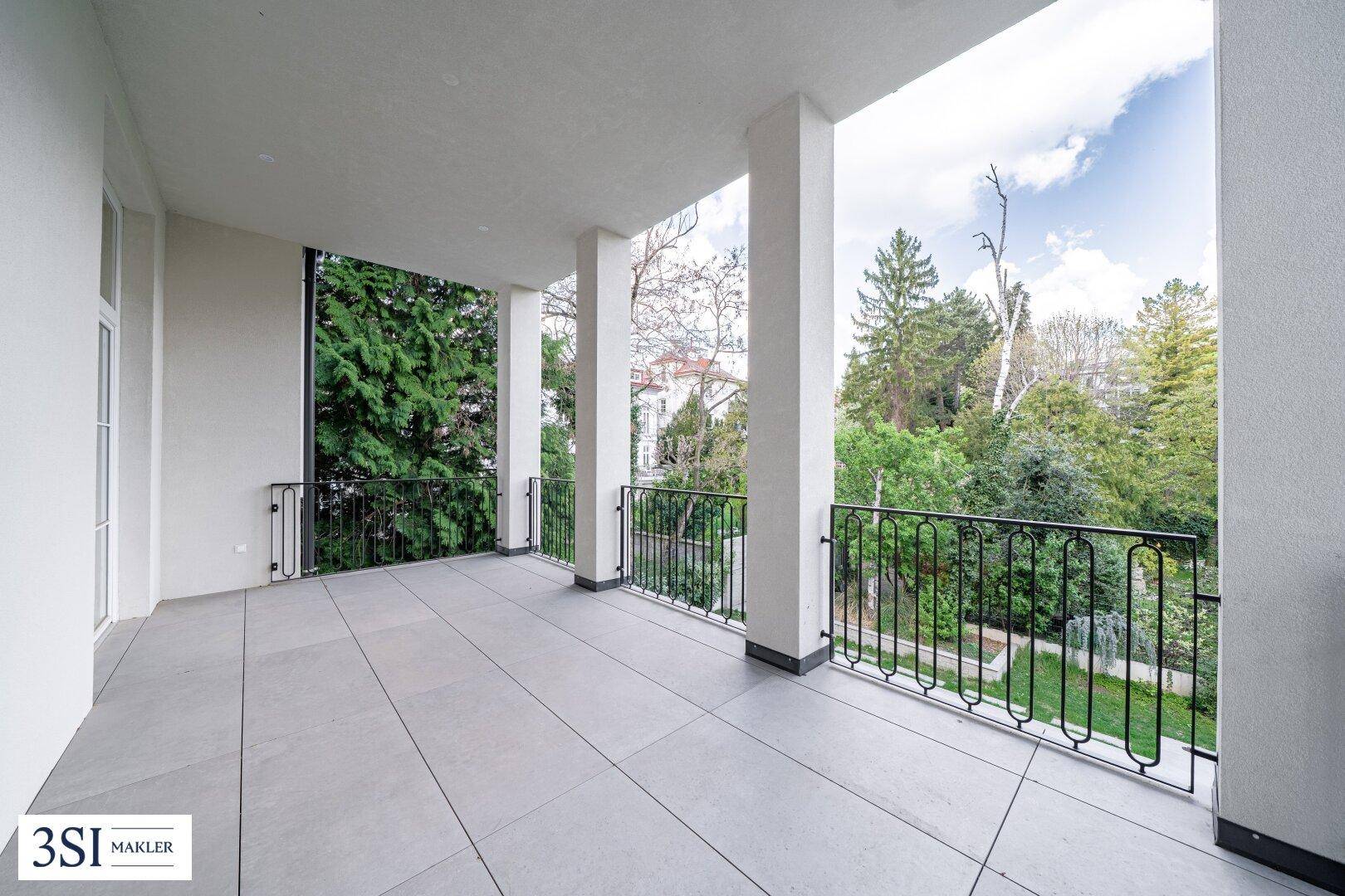 Geräumige Loggia mit Säulen und Blick auf den grünen Garten und die Umgebung.