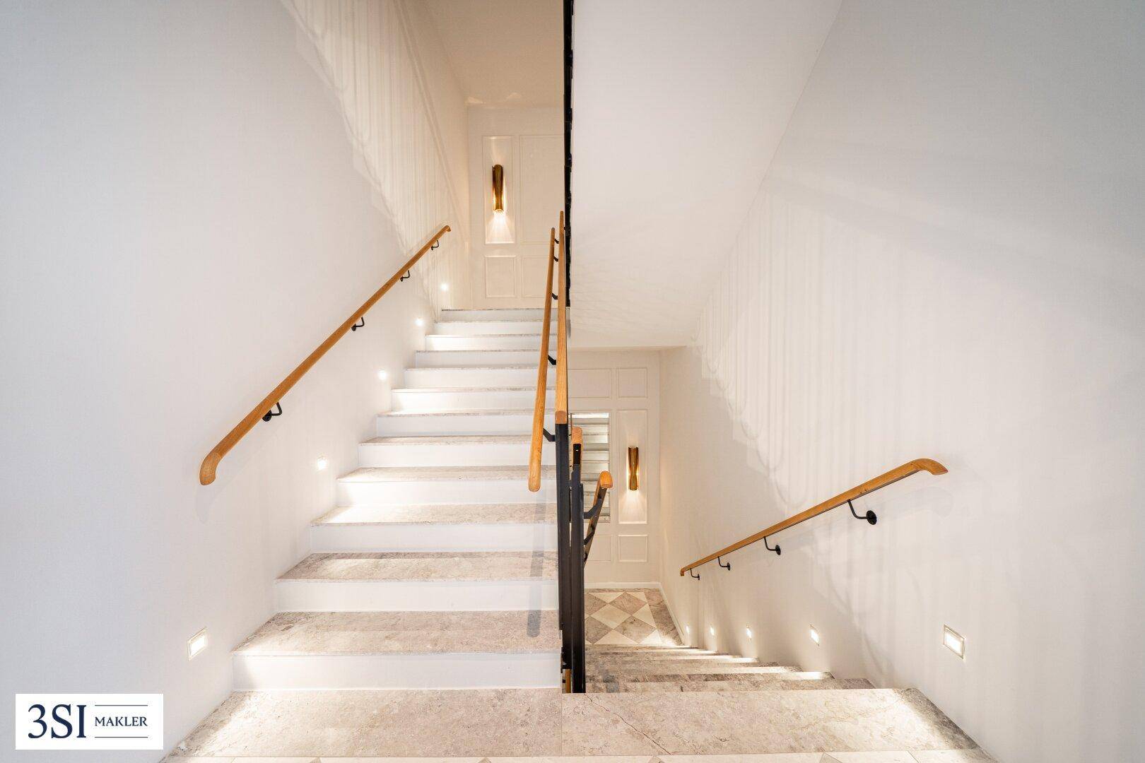 Elegante Treppe mit Holzhandläufen und integrierter Beleuchtung, die die Etagen verbindet.