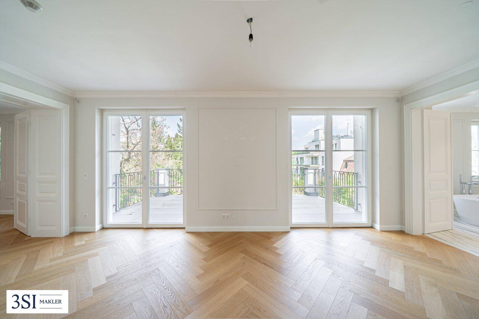 Helles Wohnzimmer mit Fischgrätparkett und zwei großen Fenstertüren zum Balkon.