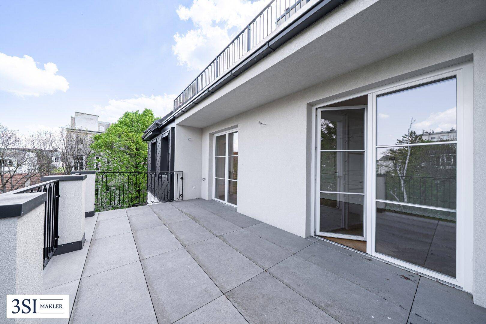 Weitläufige Terrasse mit Schiebetüren zu den Innenräumen und Blick auf die Umgebung.