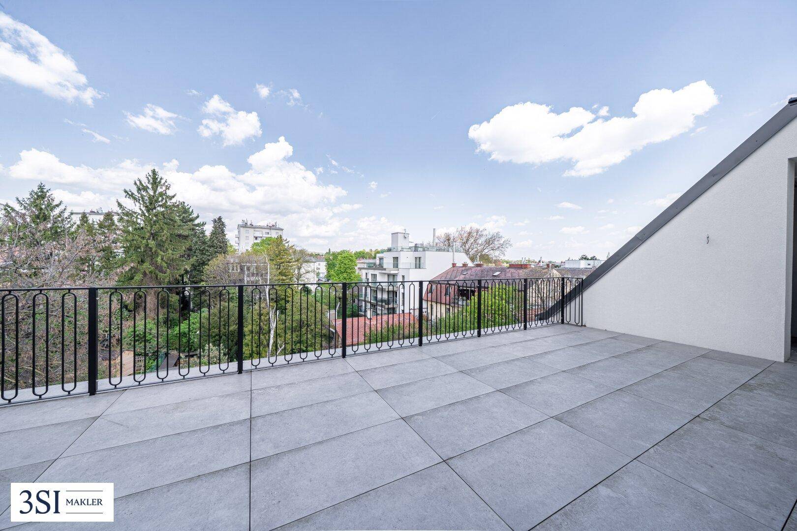 Weitläufige Dachterrasse mit Blick auf die umliegende Bebauung und viel Grün.