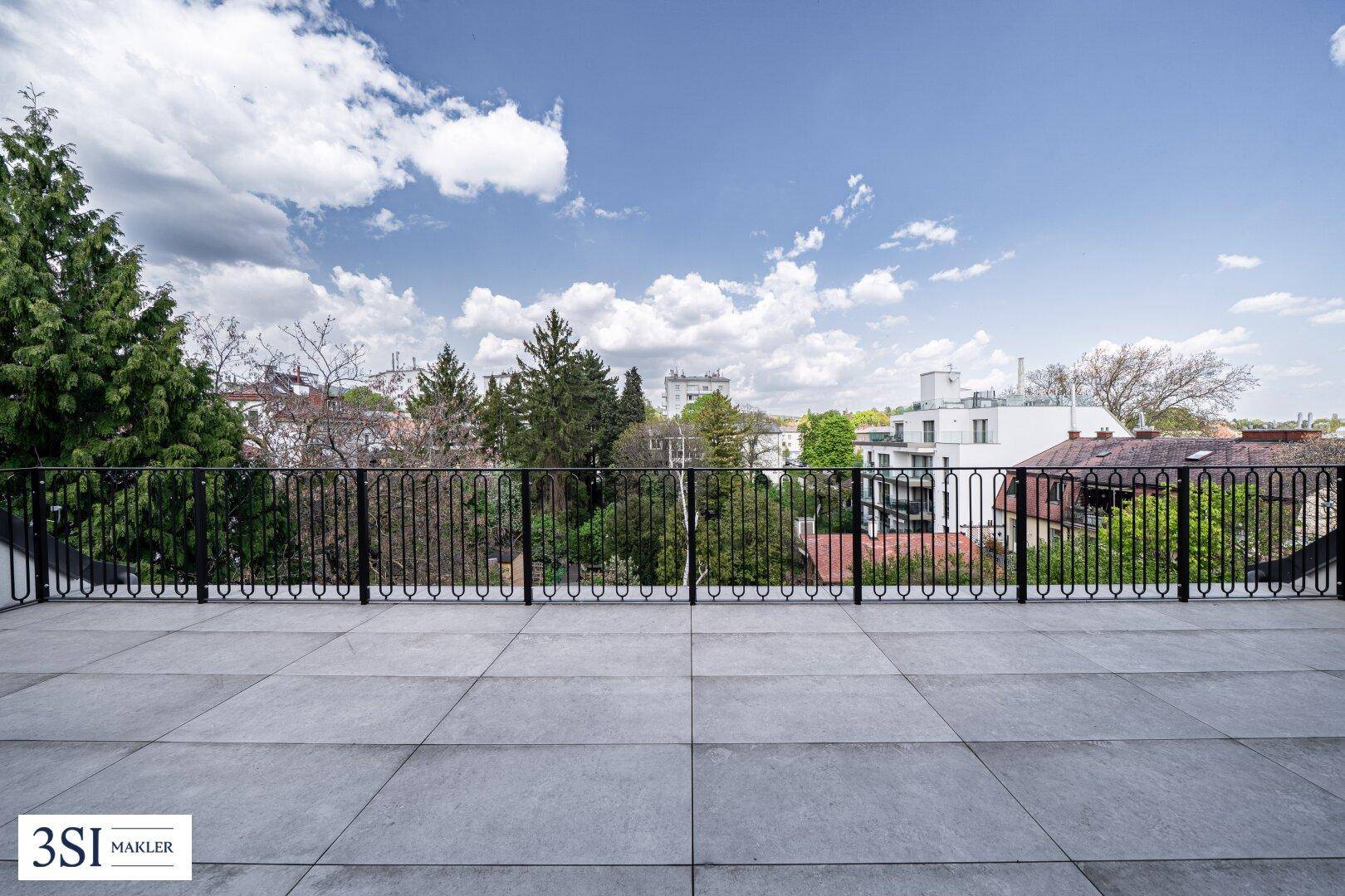 Große Dachterrasse mit weitem Blick über die Dächer und grüne Umgebung.