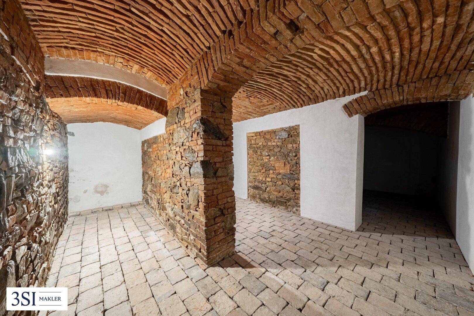 Historischer Gewölbekeller mit Ziegelwänden und -decken, ideal für Weinlagerung.
