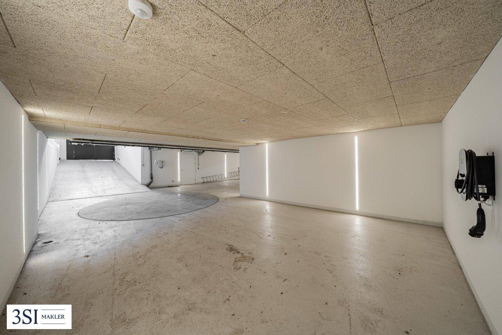 Moderne Tiefgarage mit EV-Ladestation und indirekter Beleuchtung.