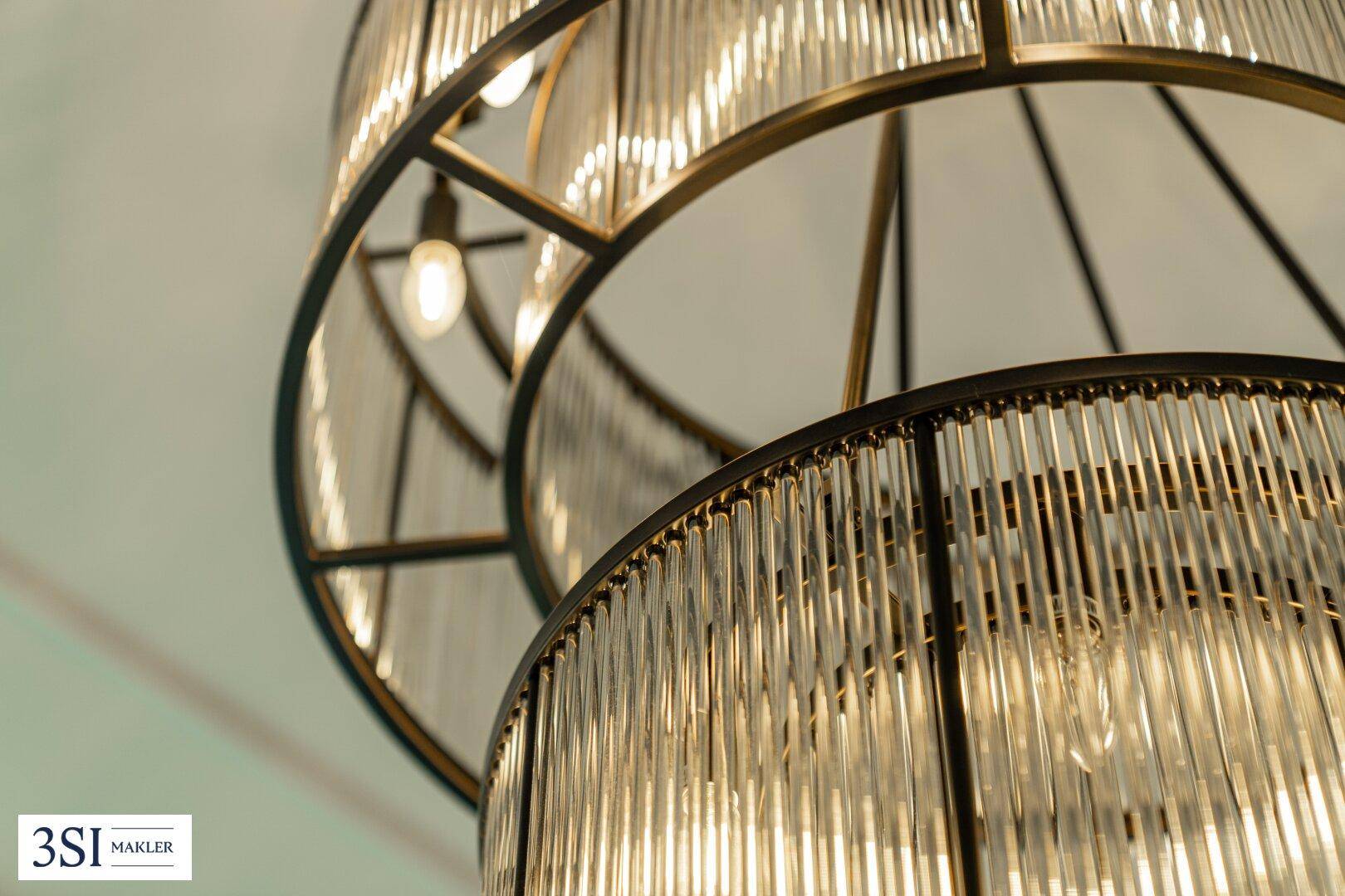 Detailaufnahme eines modernen Kronleuchters mit Glasstäben und Metallrahmen.