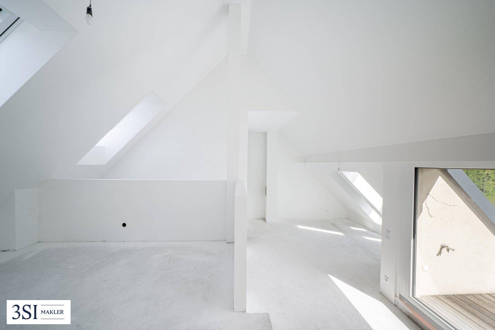 Heller, unfertiger Dachbodenraum mit schrägen Decken und Dachfenstern, bereit für den Ausbau.