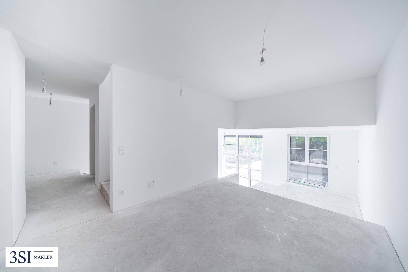 Geräumiger, unfertiger Raum mit großen Fenstern und Betonboden, ideal für individuelle Gestaltung.
