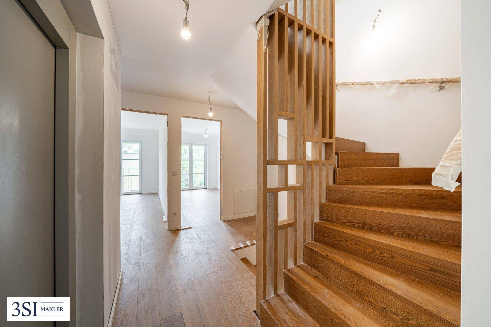 Heller Flur mit einer eleganten Holztreppe, die die verschiedenen Ebenen des Hauses verbindet.