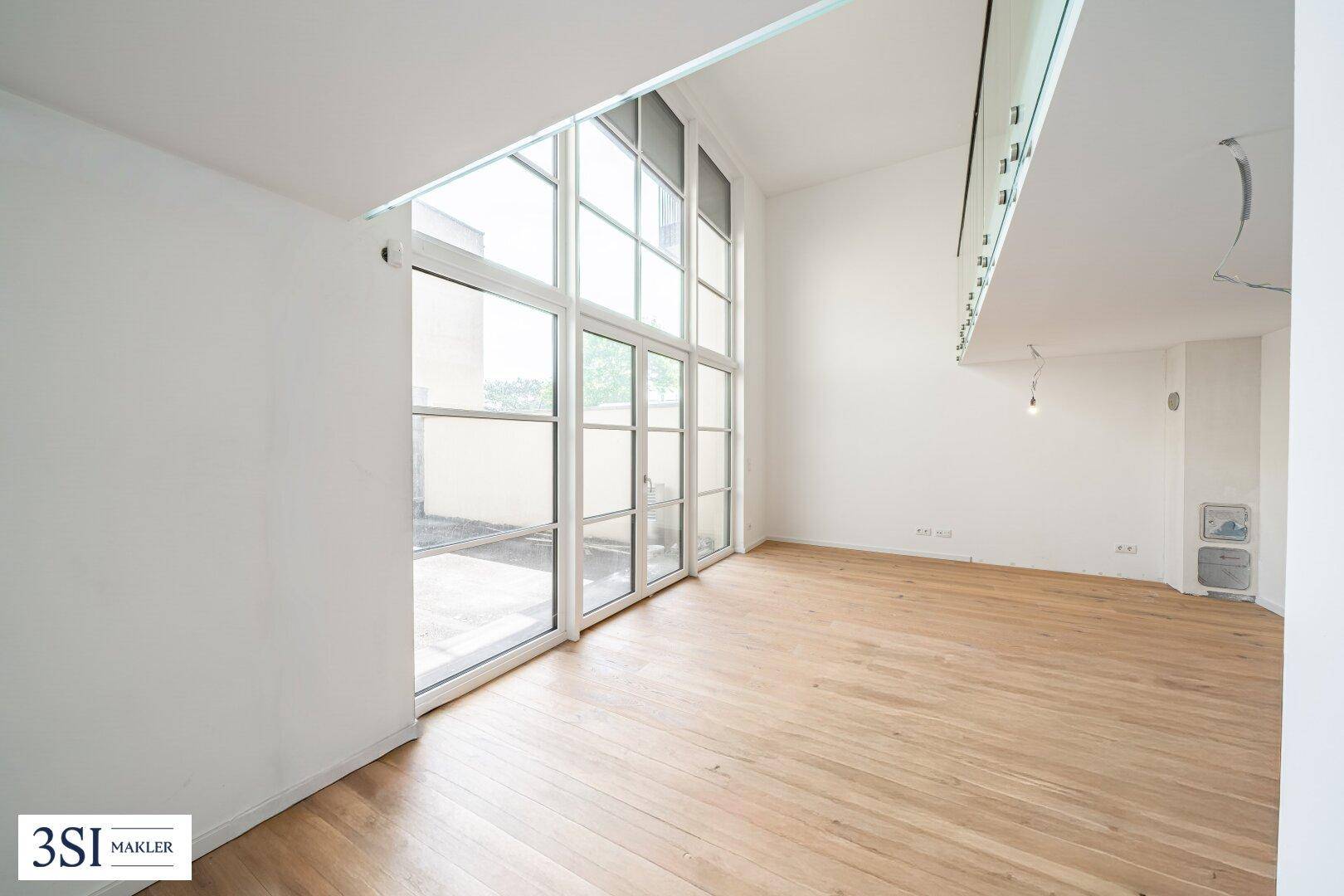 Geräumiger, heller Wohnraum mit hohen Fenstern und Holzboden, der viel Gestaltungspotenzial bietet.