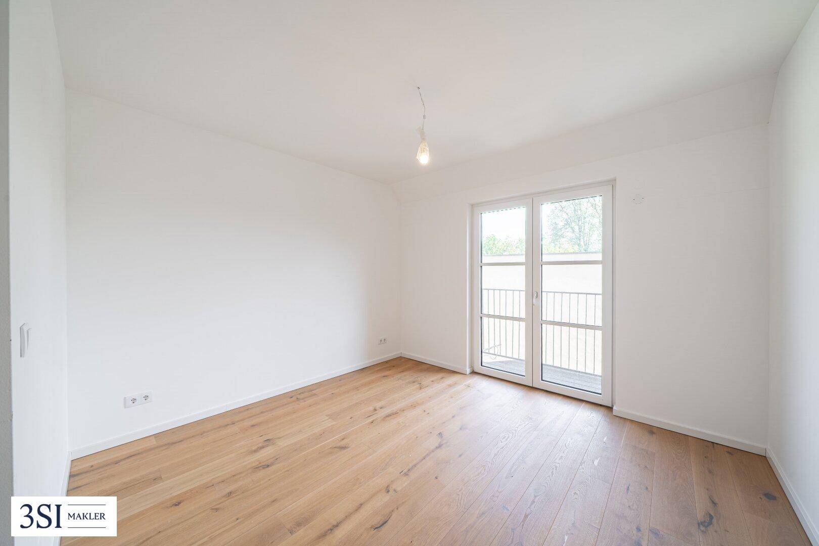 Geräumiges Schlafzimmer mit Holzboden und Balkontür, das viel natürliches Licht empfängt.