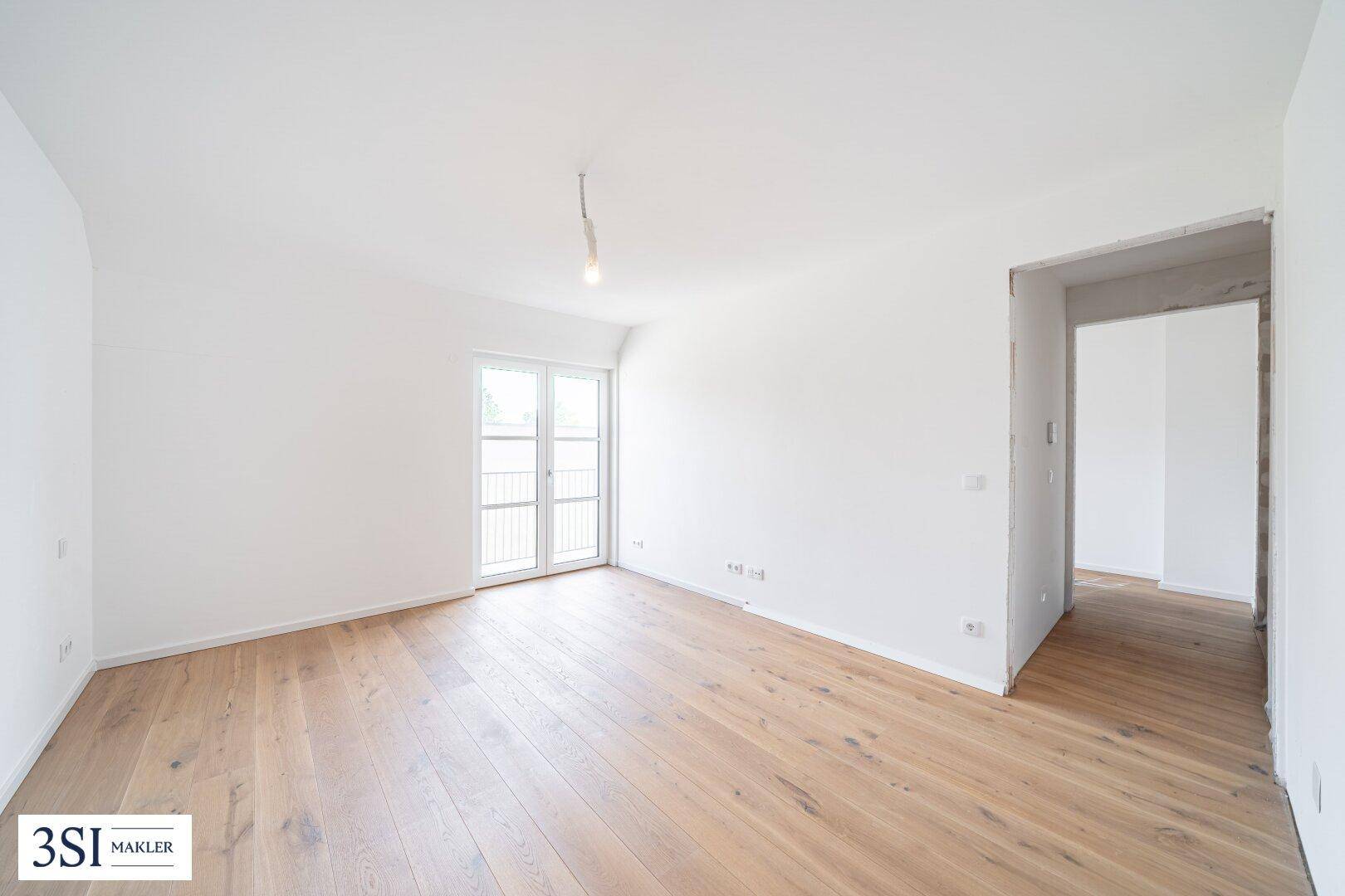 Helles Schlafzimmer mit Holzboden und Balkontür, das eine angenehme Wohnatmosphäre schafft.