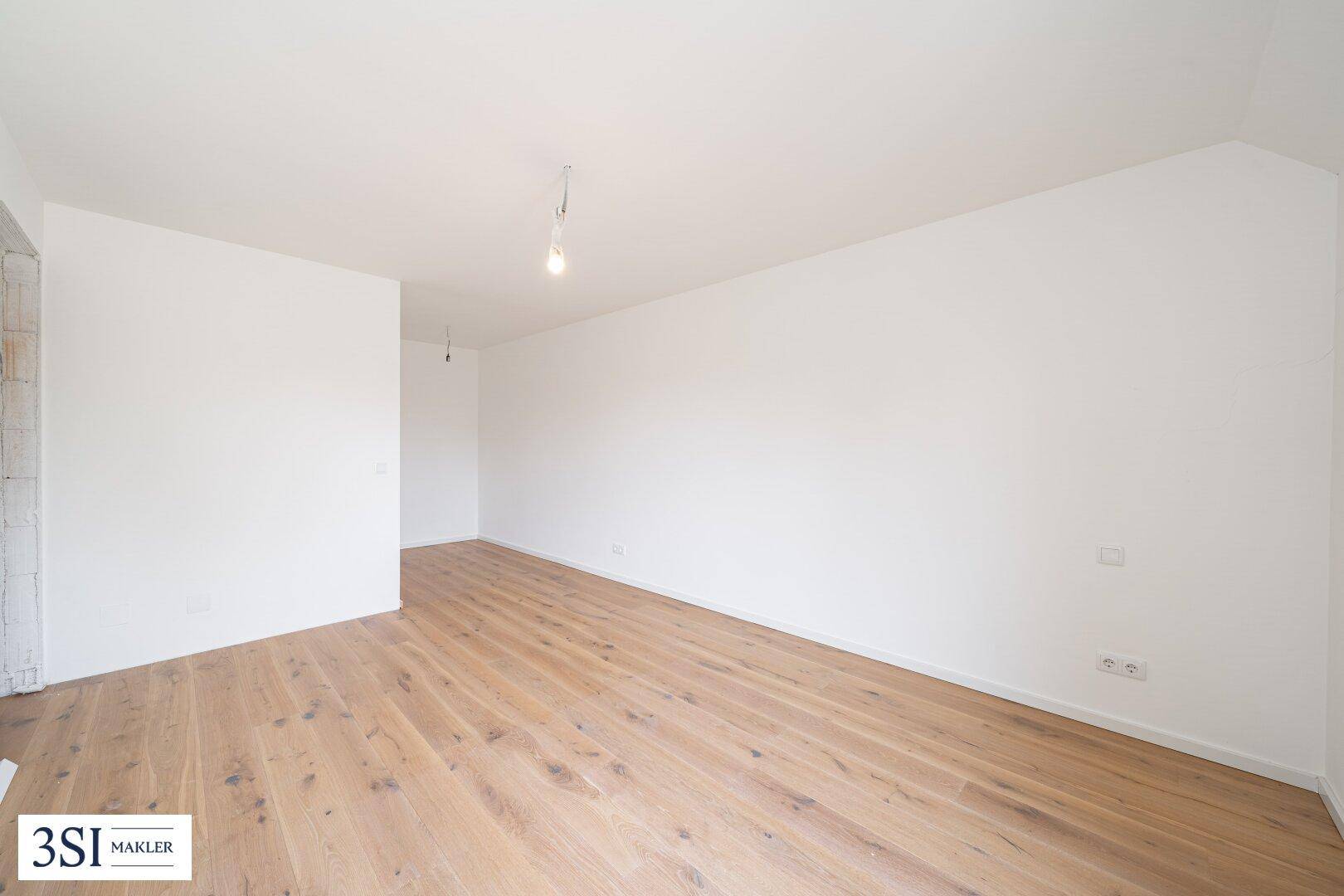 Leeres Schlafzimmer mit hellem Holzboden und weißen Wänden, bereit für individuelle Gestaltung.