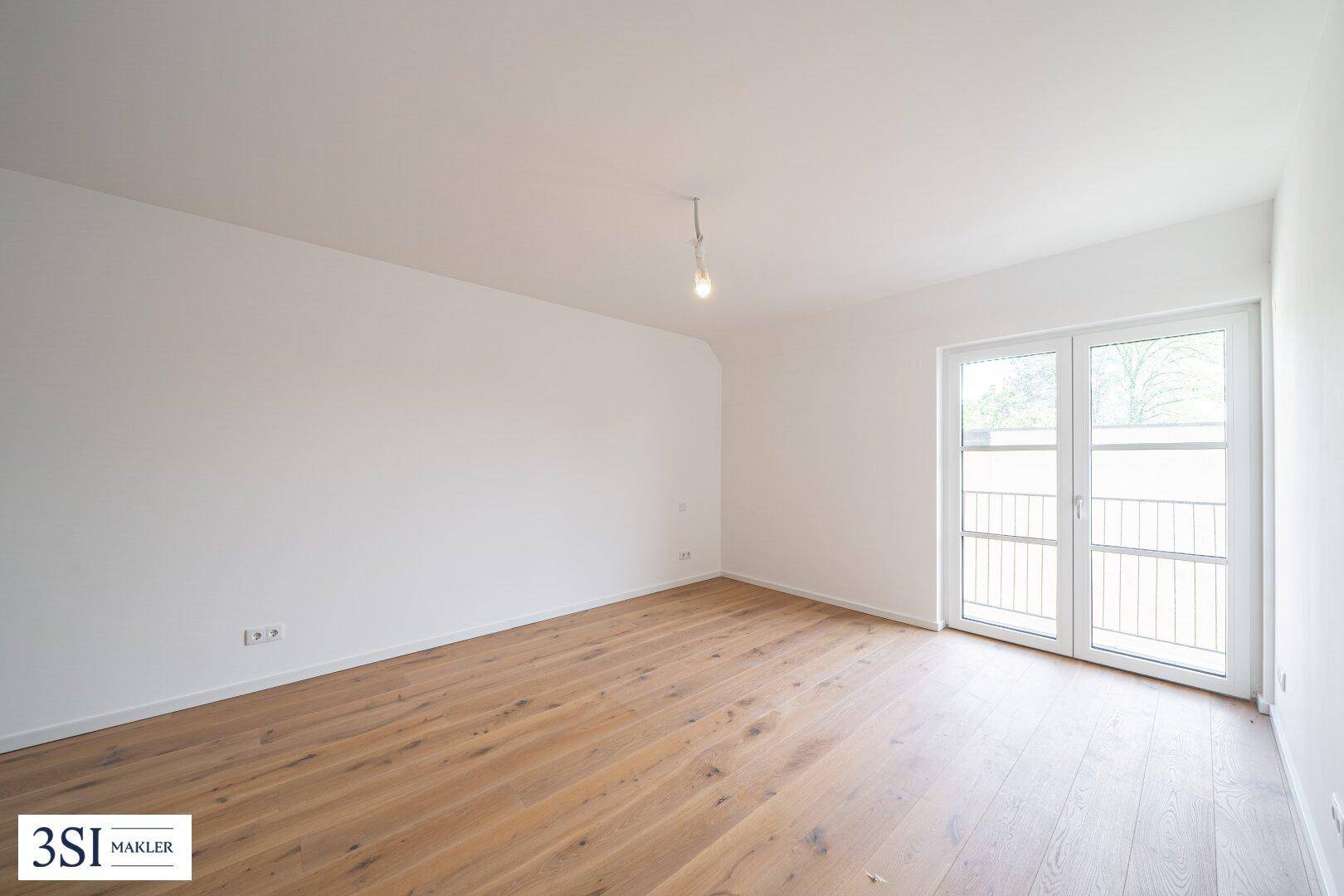 Geräumiges Schlafzimmer mit Holzboden und Balkontür, das viel Potenzial für persönliche Einrichtung bietet.