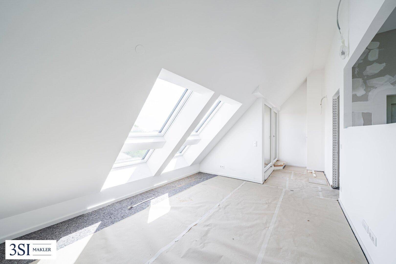 Heller Dachbodenraum mit schrägen Wänden und großen Dachfenstern für viel Tageslicht.