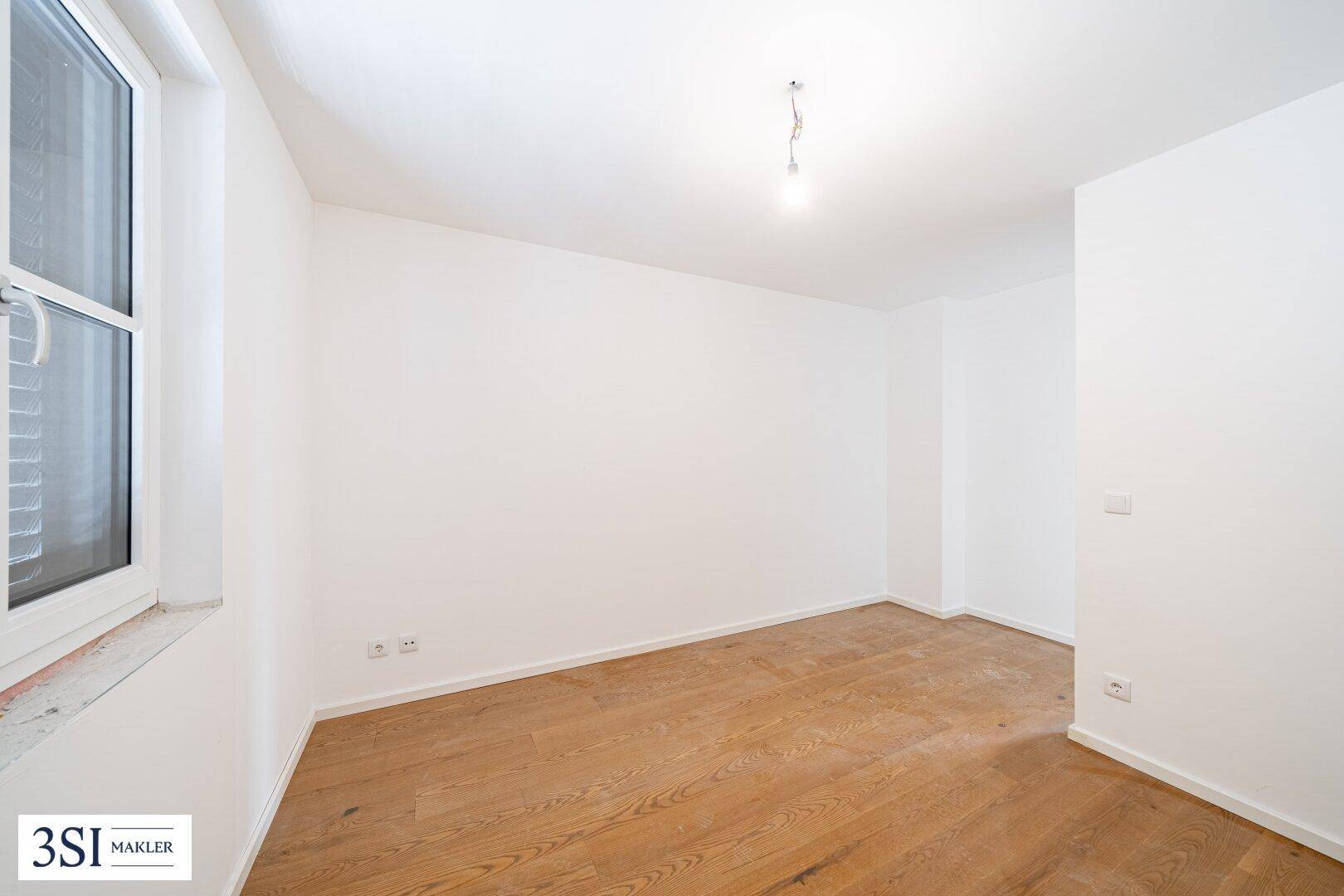 Heller, unmöblierter Raum mit Holzboden und einem Fenster, ideal für individuelle Gestaltung.