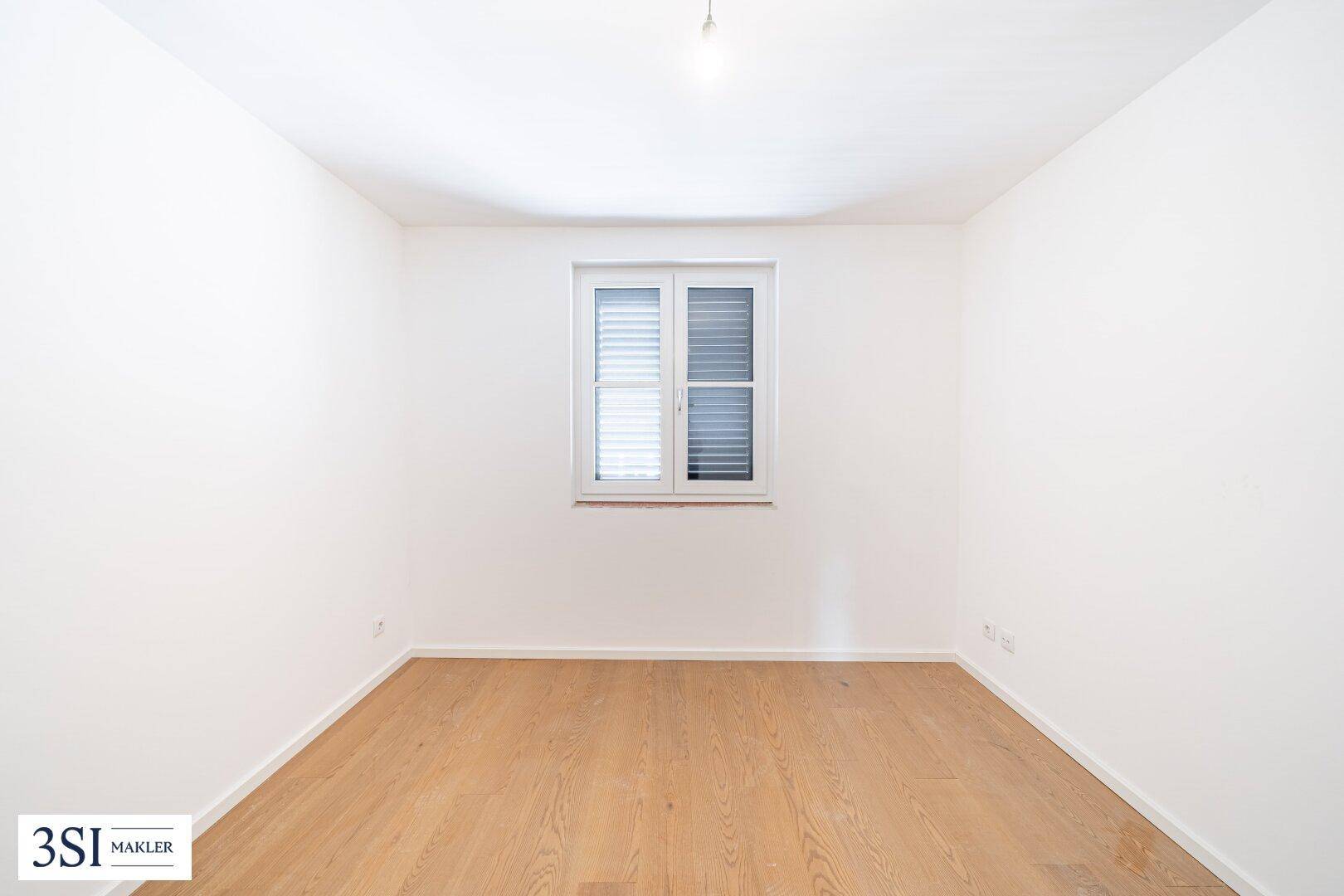 Leerer Raum mit weiß gestrichenen Wänden und einem Fenster, bereit für die Einrichtung.