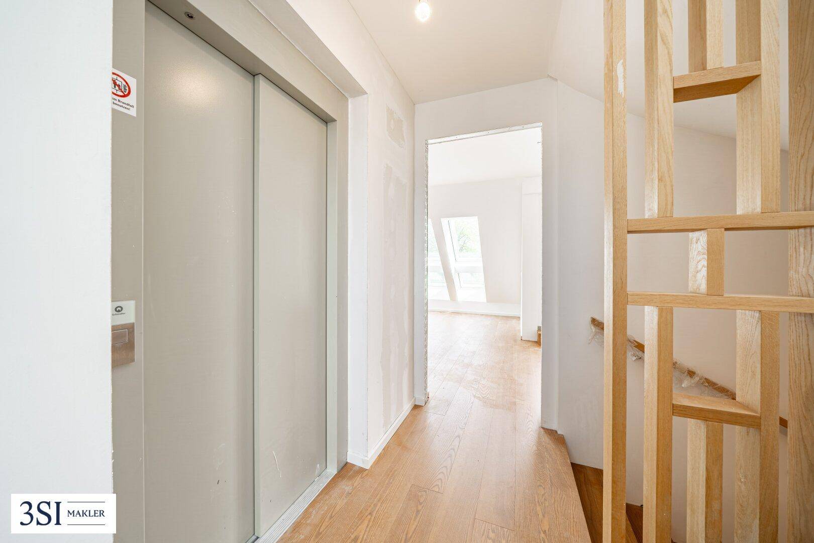 Heller Flur mit Holzboden und Zugang zu einem modernen Aufzug im Neubau.
