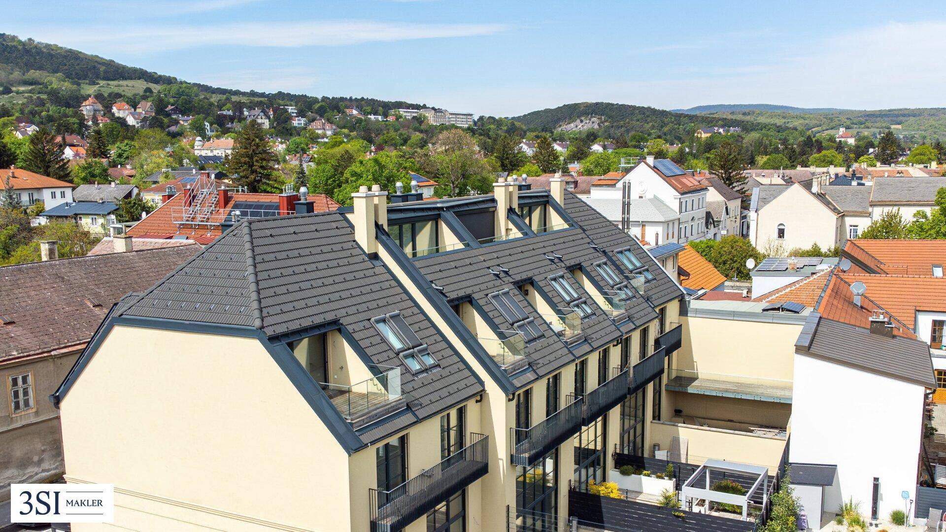 Luftaufnahme der Reihenhäuser mit Blick auf die umliegende grüne Landschaft und Berge.