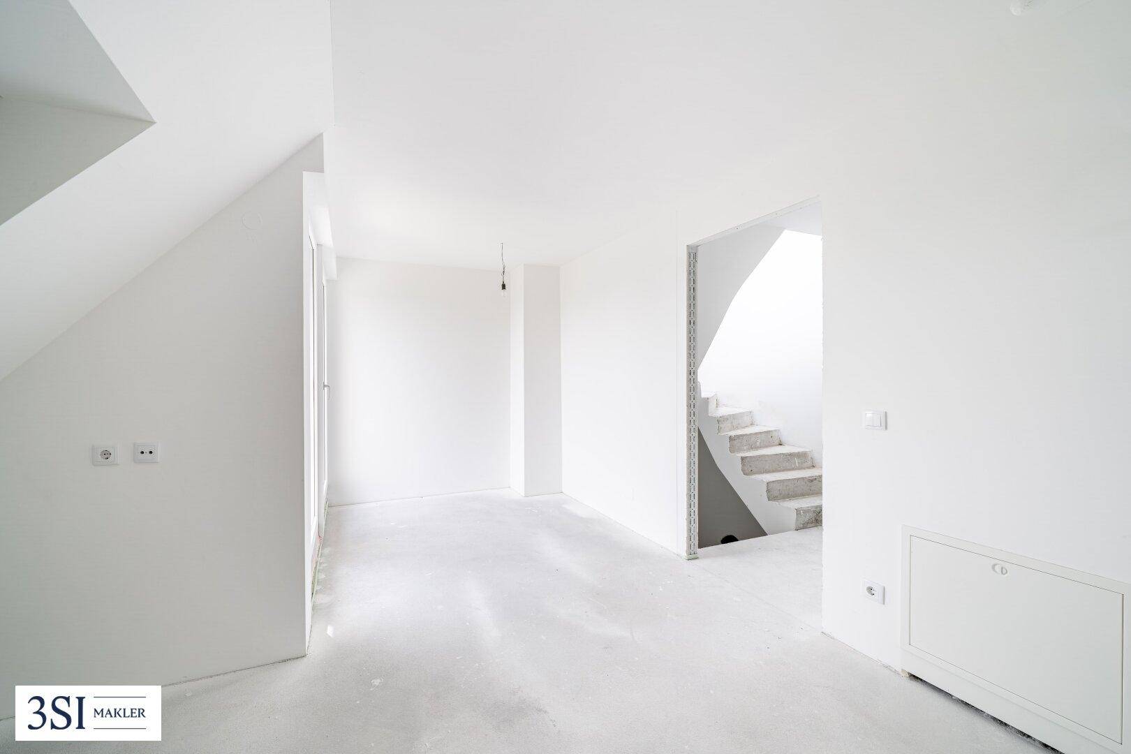 Heller Rohbau mit geschwungener Treppe und Zugang zu weiteren Räumen.