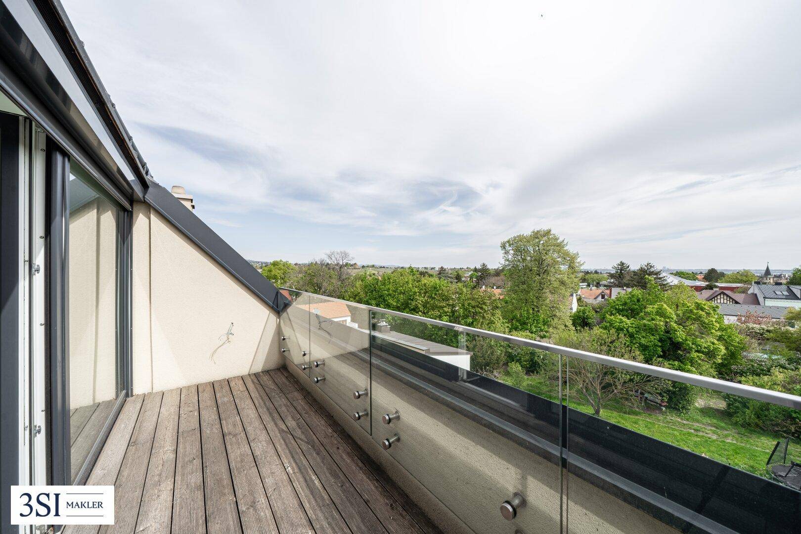 Geräumiger Balkon mit Holzbelag und Glasbrüstung, bietet weite Aussicht.