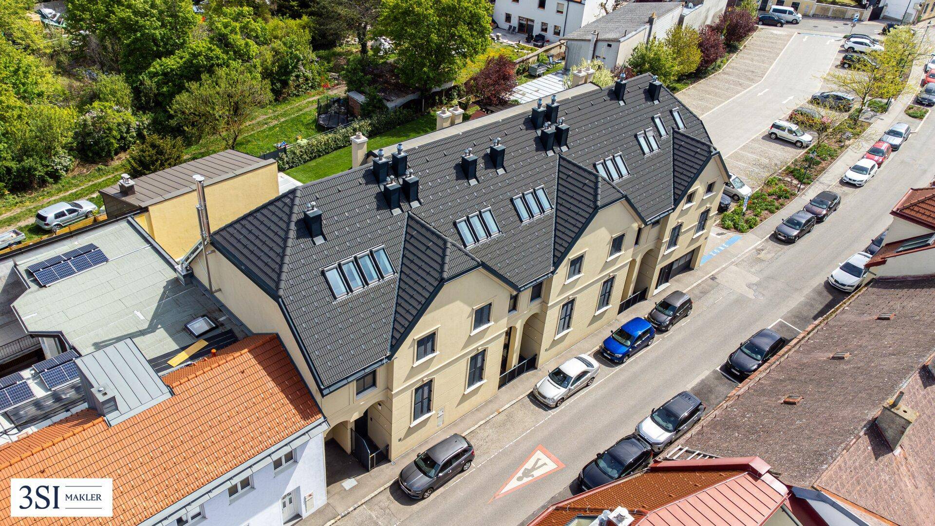 Vogelperspektive eines modernen Wohnkomplexes mit Satteldächern und umliegender Bebauung.