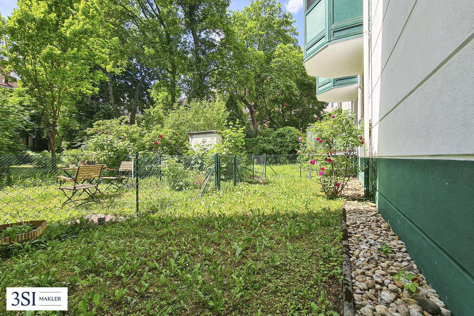 Grüner Gartenbereich mit Sitzgelegenheiten und Rosensträuchern neben dem Gebäude.