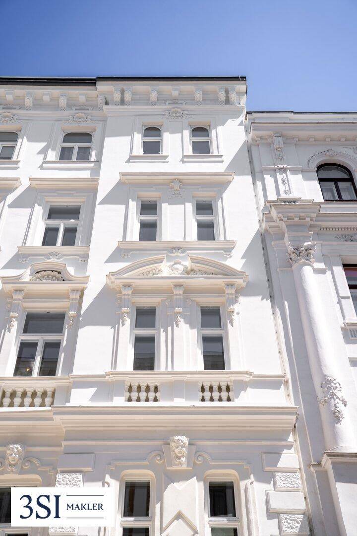 Nahaufnahme der detailreichen weißen Fassade eines klassischen Altbaus.