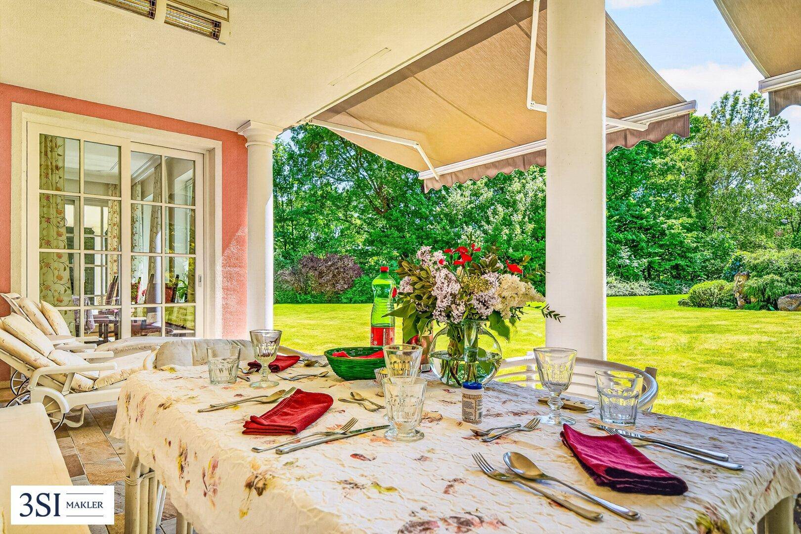 Gemütliche überdachte Terrasse mit Esstisch und Blick auf den gepflegten Garten.