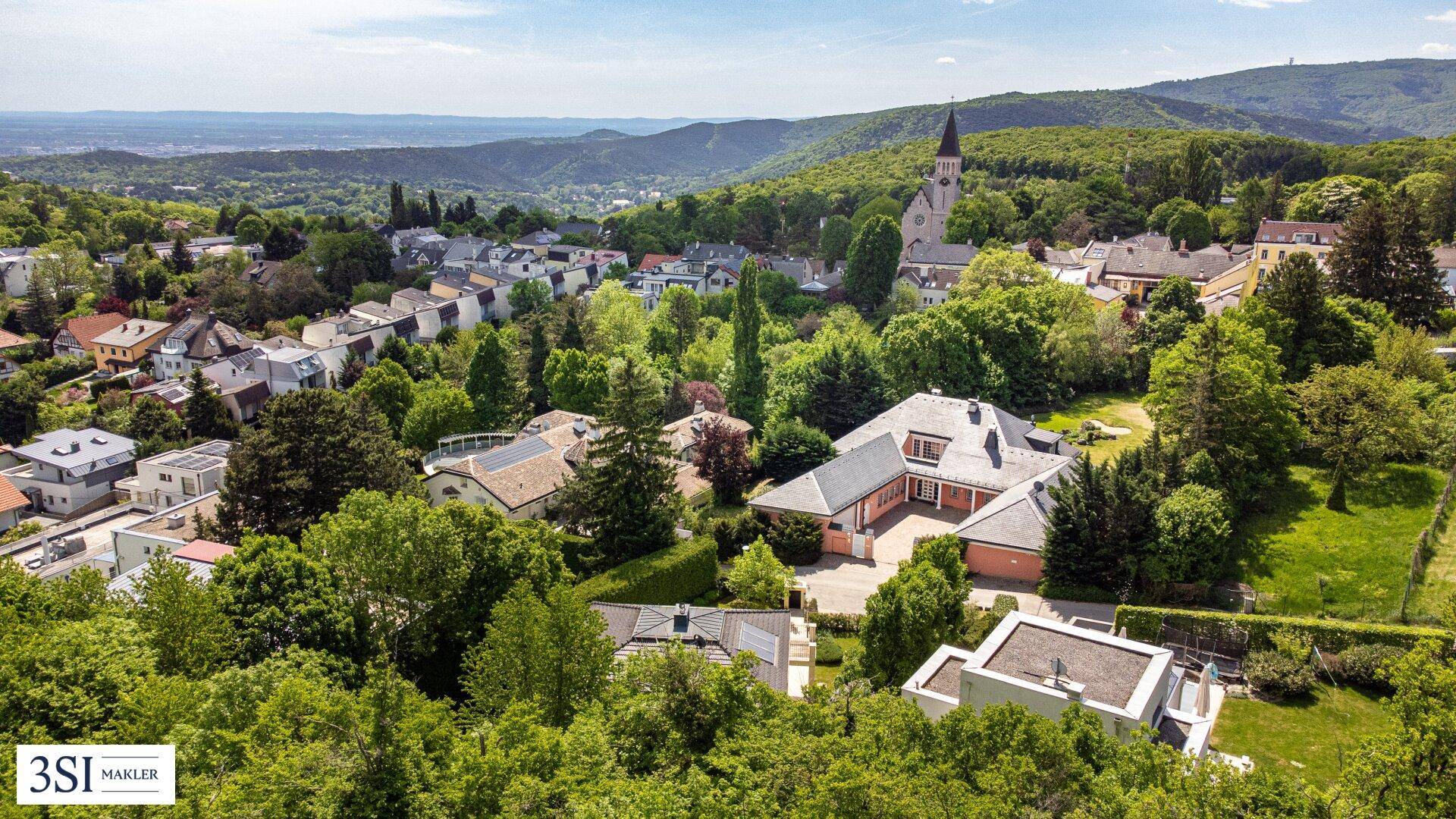Luftaufnahme der Villa und der umliegenden grünen Wohngegend mit Fernblick.