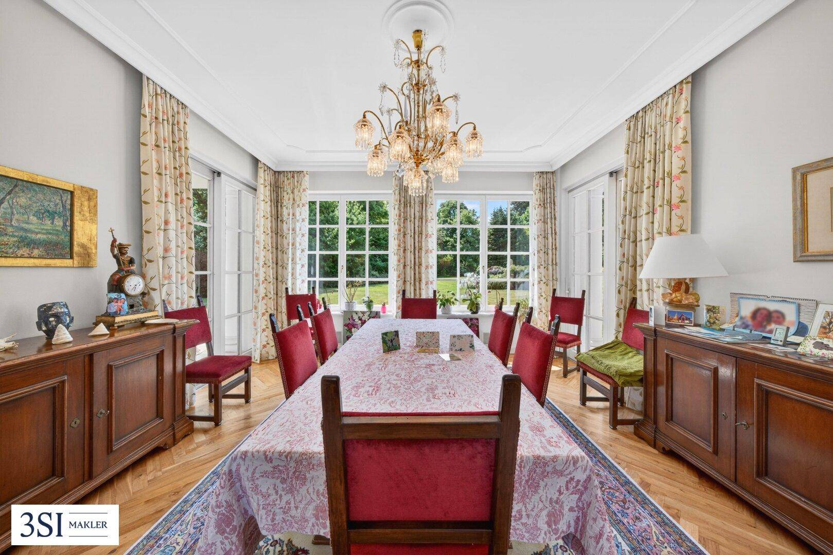 Repräsentativer Essbereich mit großem Holztisch, eleganten roten Stühlen und Kronleuchter.