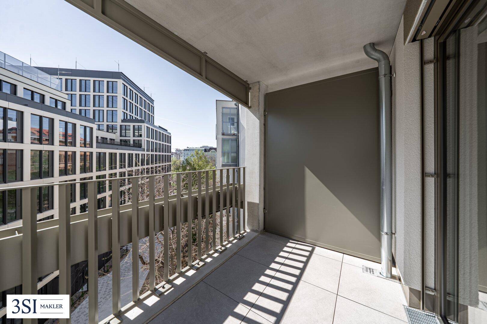 Balkon mit Fliesenboden und Blick auf moderne Gebäude in der Umgebung.