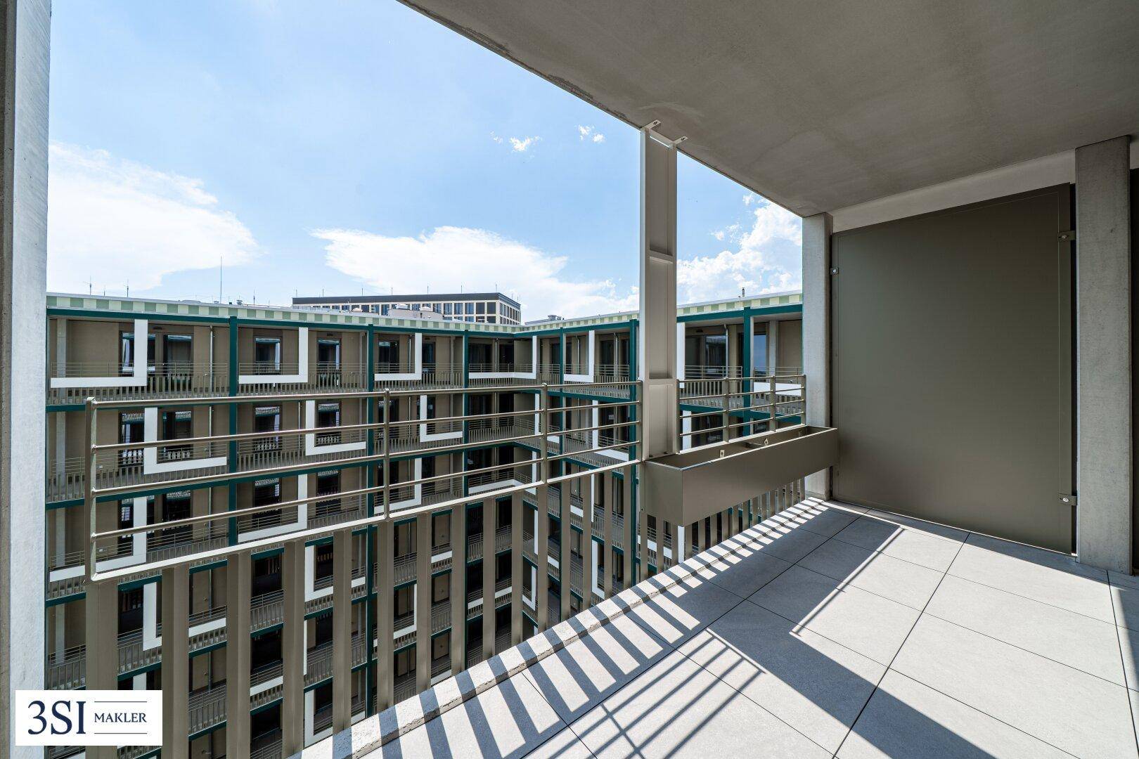 Geräumiger Balkon mit Fliesenboden und Blick auf die umliegenden modernen Wohngebäude.