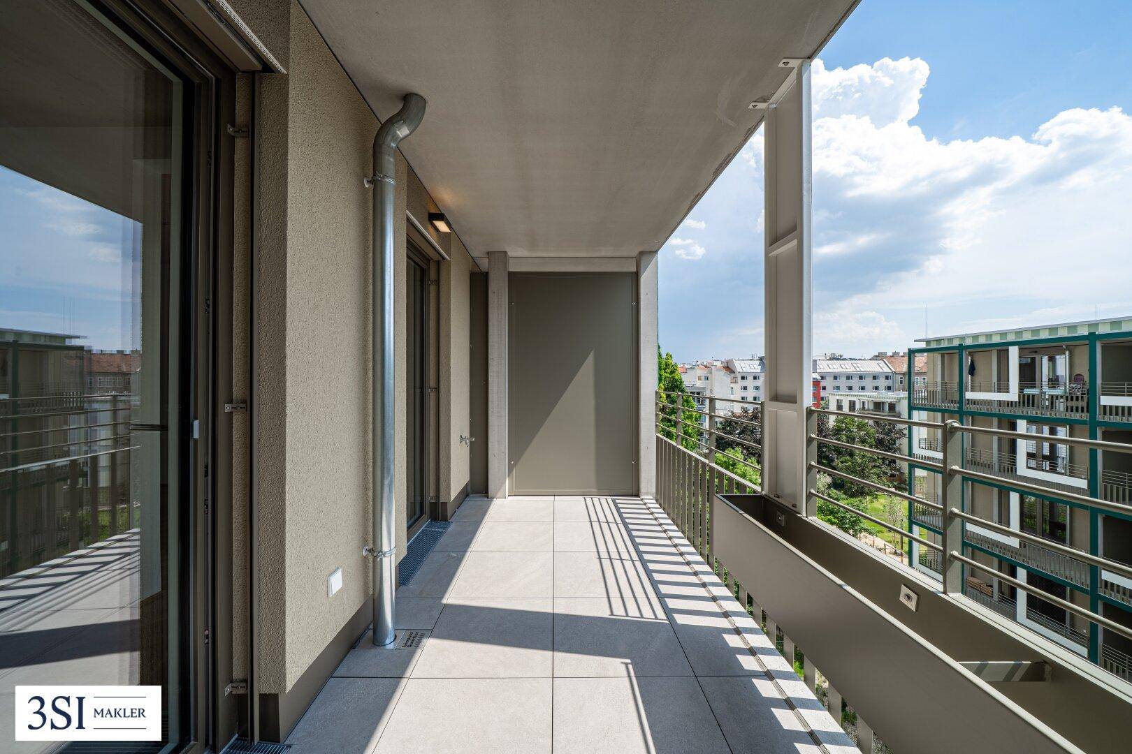 Langer, sonniger Balkon mit Fliesenboden und weitem Blick über die Stadtlandschaft.