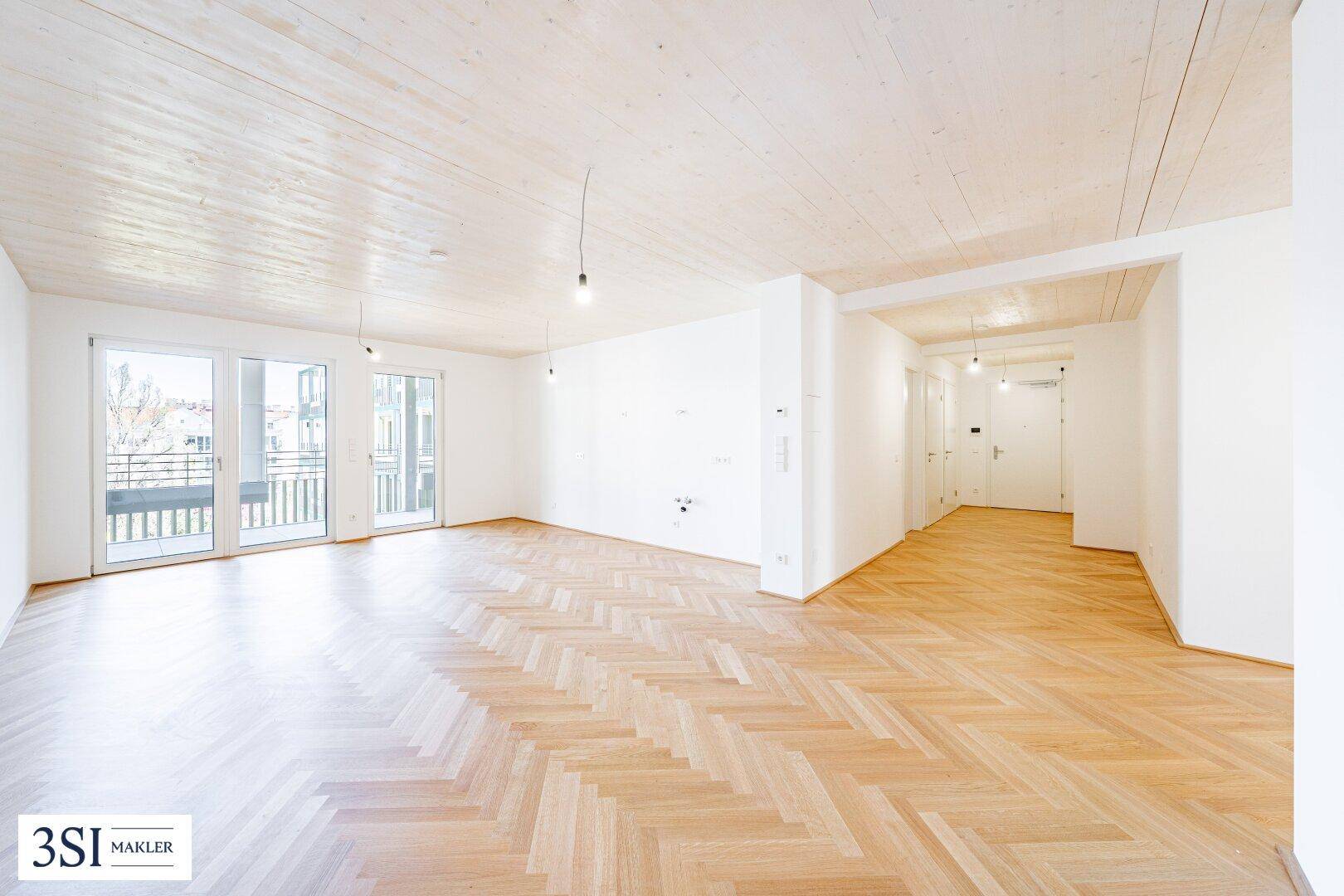 Geräumiges, helles Zimmer mit Fischgrätparkett und Zugang zu einem Balkon, bereit zur Einrichtung.