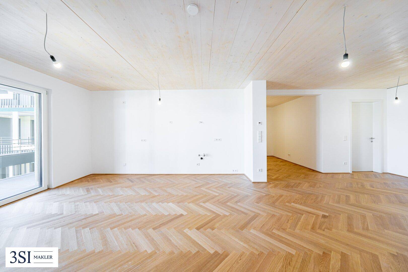 Heller, leerer Raum mit Fischgrätparkett und Holzbalkendecke, bereit für individuelle Gestaltung.