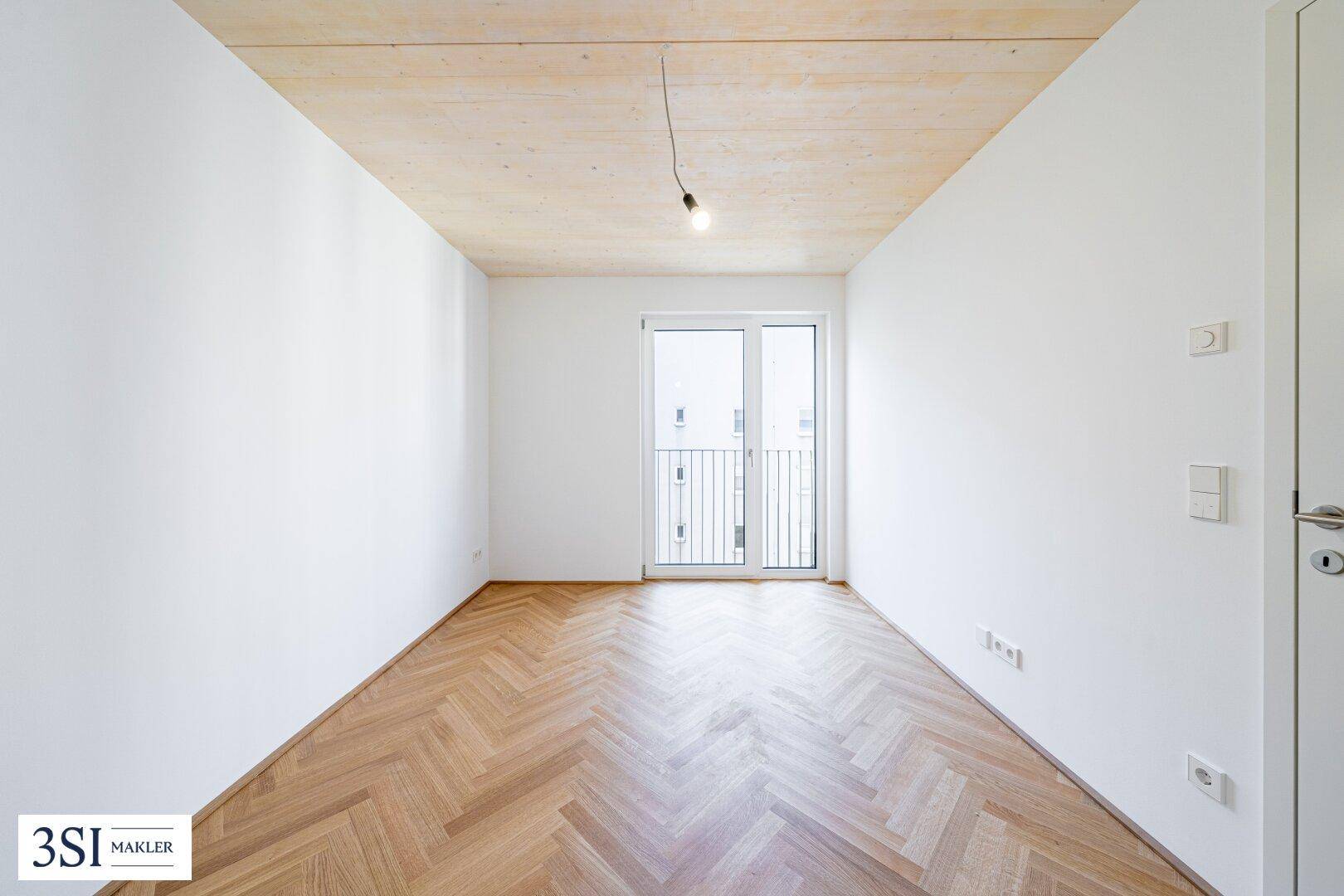 Helles Zimmer mit Fischgrätparkett und französischem Balkon, bietet eine angenehme Wohnatmosphäre.
