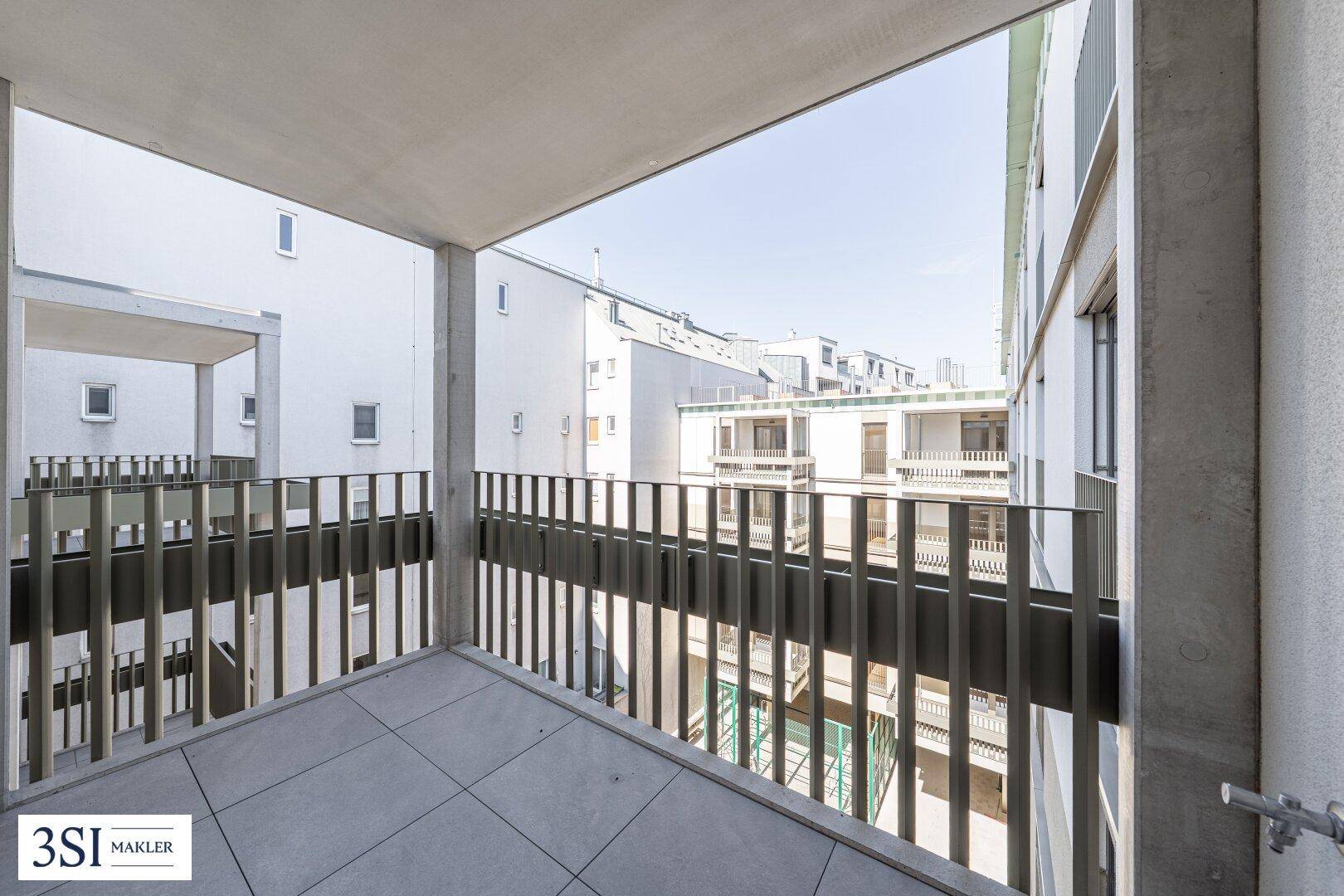 Geräumiger Balkon mit Fliesenboden und Blick auf die umliegenden modernen Gebäude.