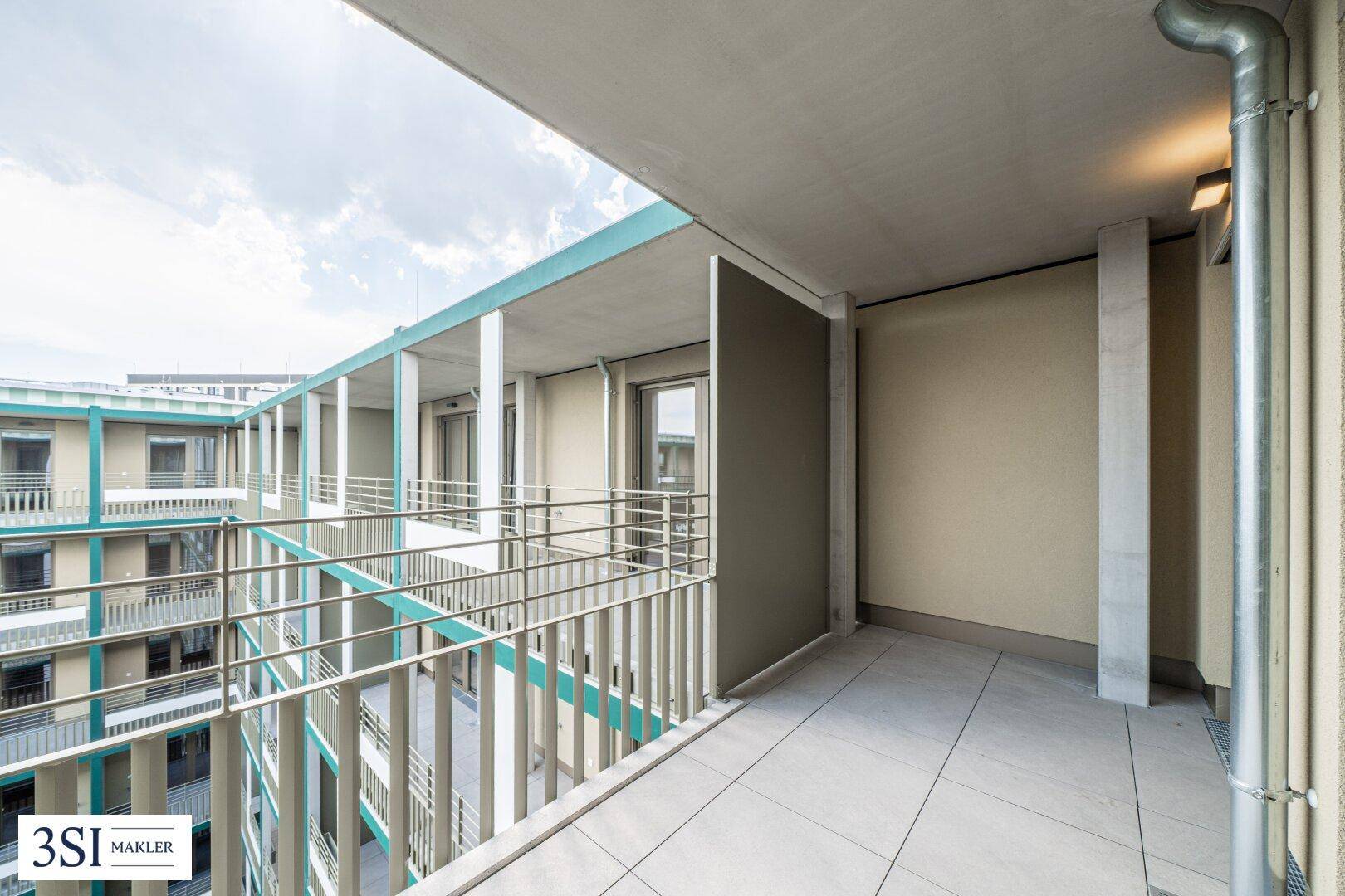 Heller Balkon mit Blick auf den Innenhof und die moderne Architektur des Gebäudes.