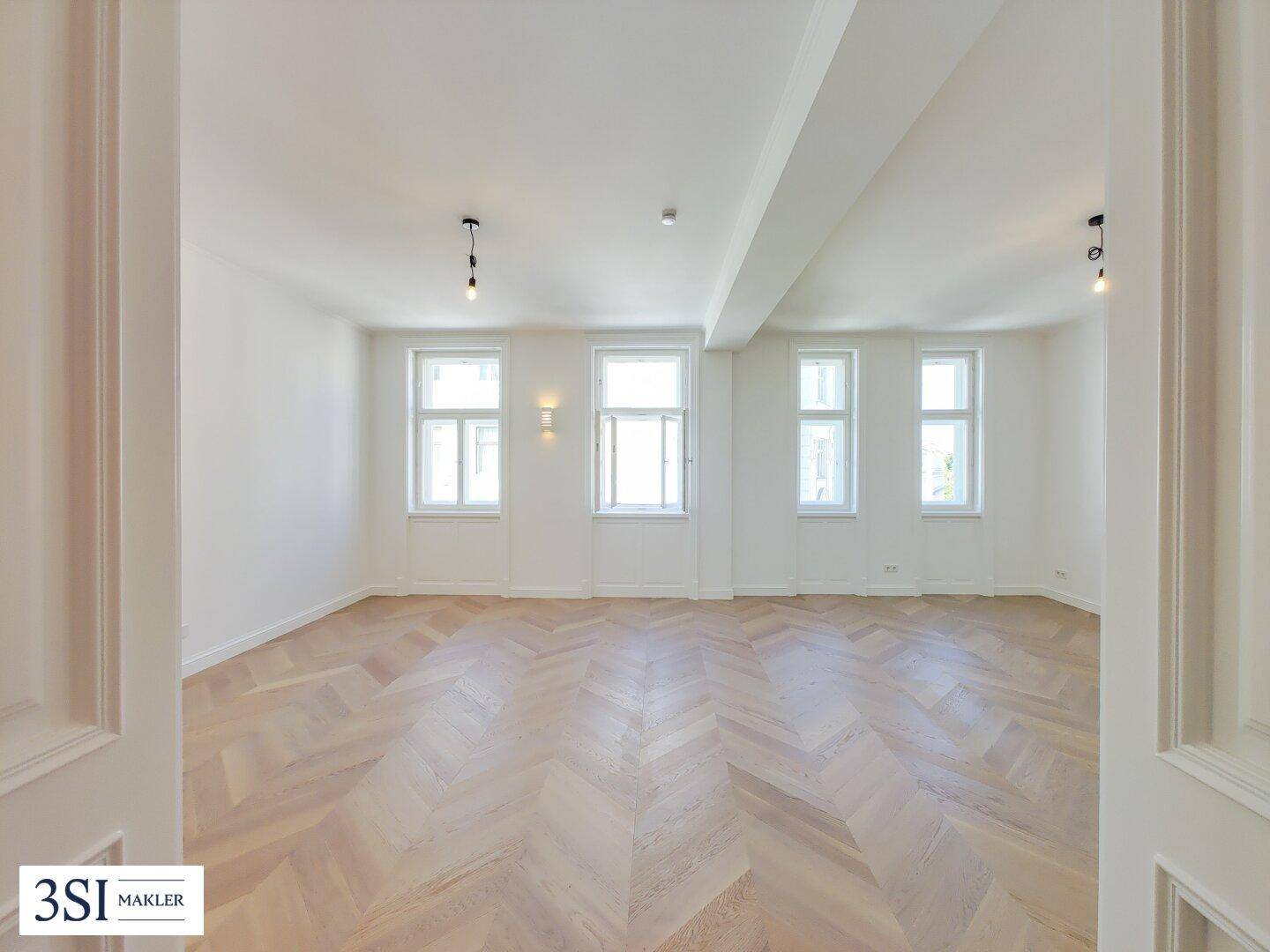 Helles, leeres Wohnzimmer mit elegantem Fischgrätparkett und hohen Decken, bereit zum Einzug.